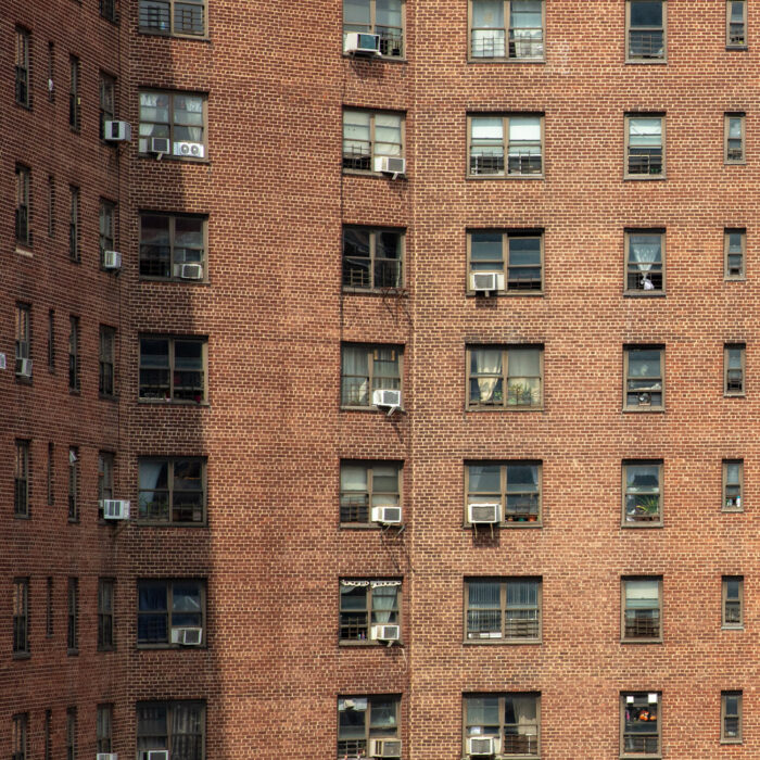 Apartment building with room air conditioners hanging out the windows